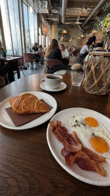 AI render in a candid style: croissant beside bacon and eggs