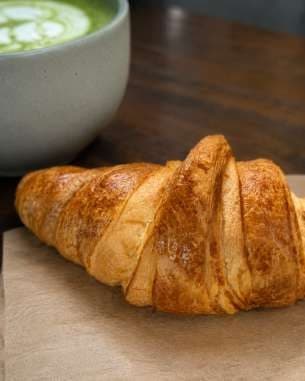 AI render: close-up of a croissant beside a matcha latte