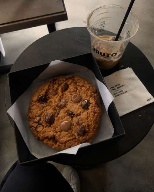AI render in a candid style: a cookie in its box beside an iced coffee